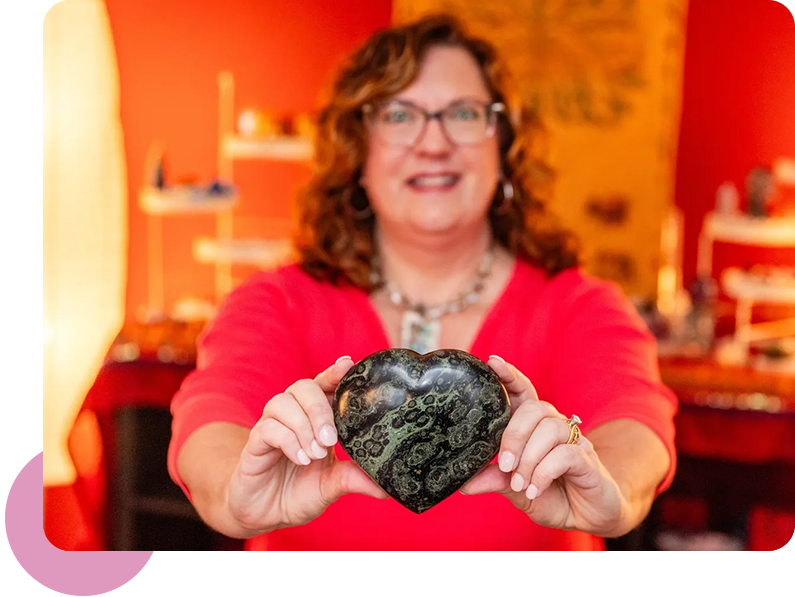 A woman holding up a heart shaped rock.